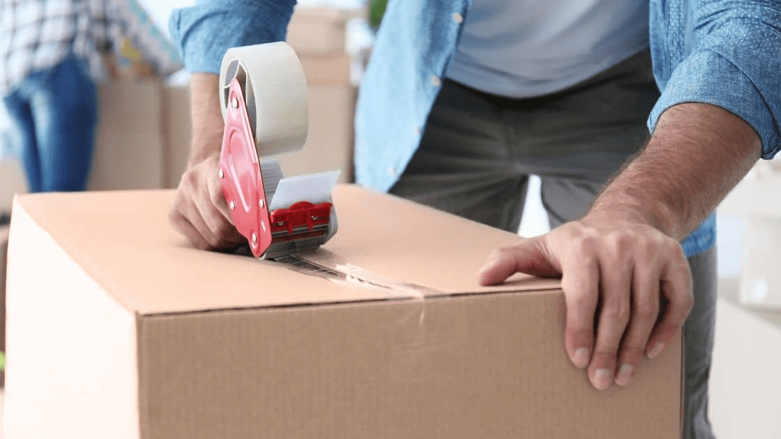 A person packing supplies into a moving box