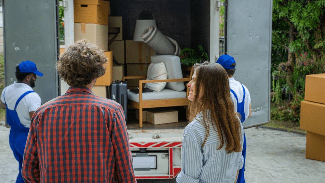 A professional moving crew carrying boxes and furniture into a new house