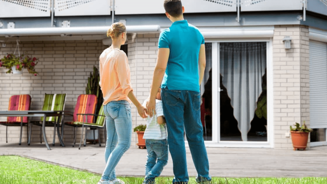 A family standing in front of their current house, discussing how to make more space for their growing family