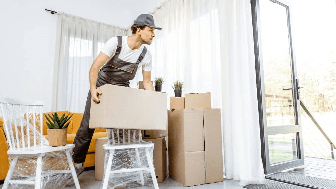 A professional moving crew carrying boxes and furniture out of a house