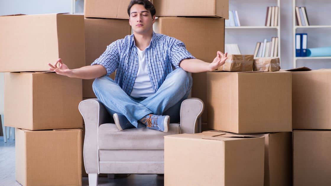 A man meditates amongst moving boxes. Finding a quality cheap movers company may be challenging!