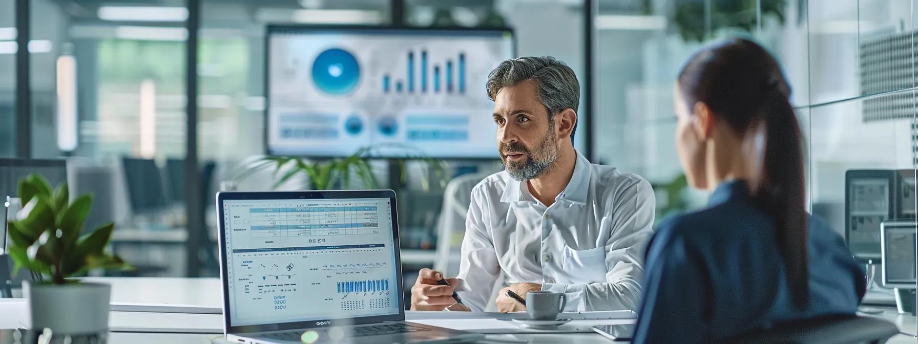Explore Pricing Dynamics of Moving Services Based on Timing 3 a modern, sleek office setting features a professional discussing moving estimates with a representative, with a laptop open displaying a detailed inventory spreadsheet and transparent pricing charts on the screen.